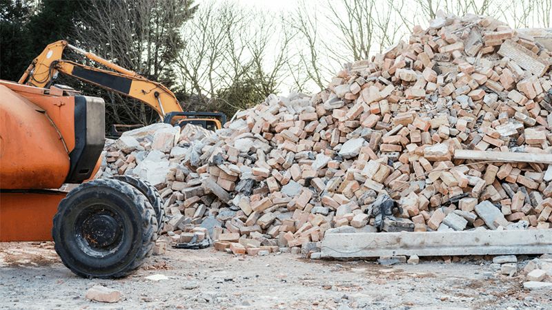 A Large Pile Of Broken Bricks And Concrete Debris Sits At A Demolition Site